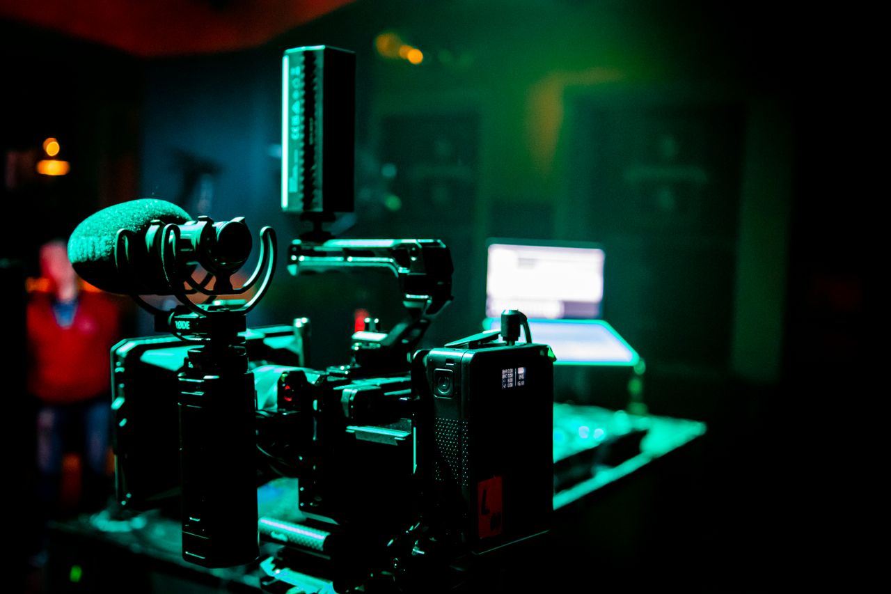 Close-up of professional camera and microphone with green lighting in a modern studio setting.